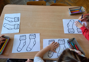 Dzieci kolorują kolorowankę przedstawiającą skarpetki.